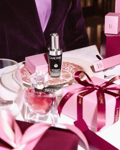 Lancome beauty products and pink gift boxes arranged on a festive dining table.
