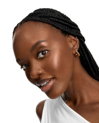 Smiling woman with long braids and glowing skin.