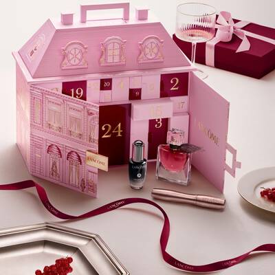 An open pink Lancome townhouse advent calendar displayed with beauty products and a red ribbon.