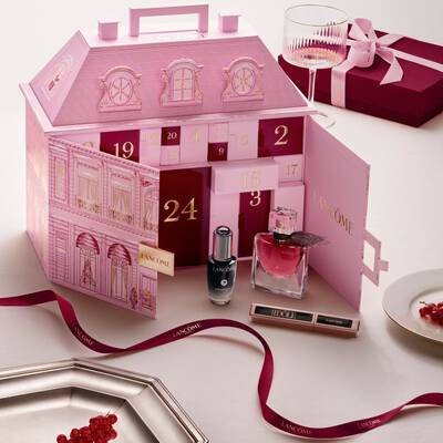 An open pink Lancome townhouse advent calendar displayed with beauty products and a red ribbon.