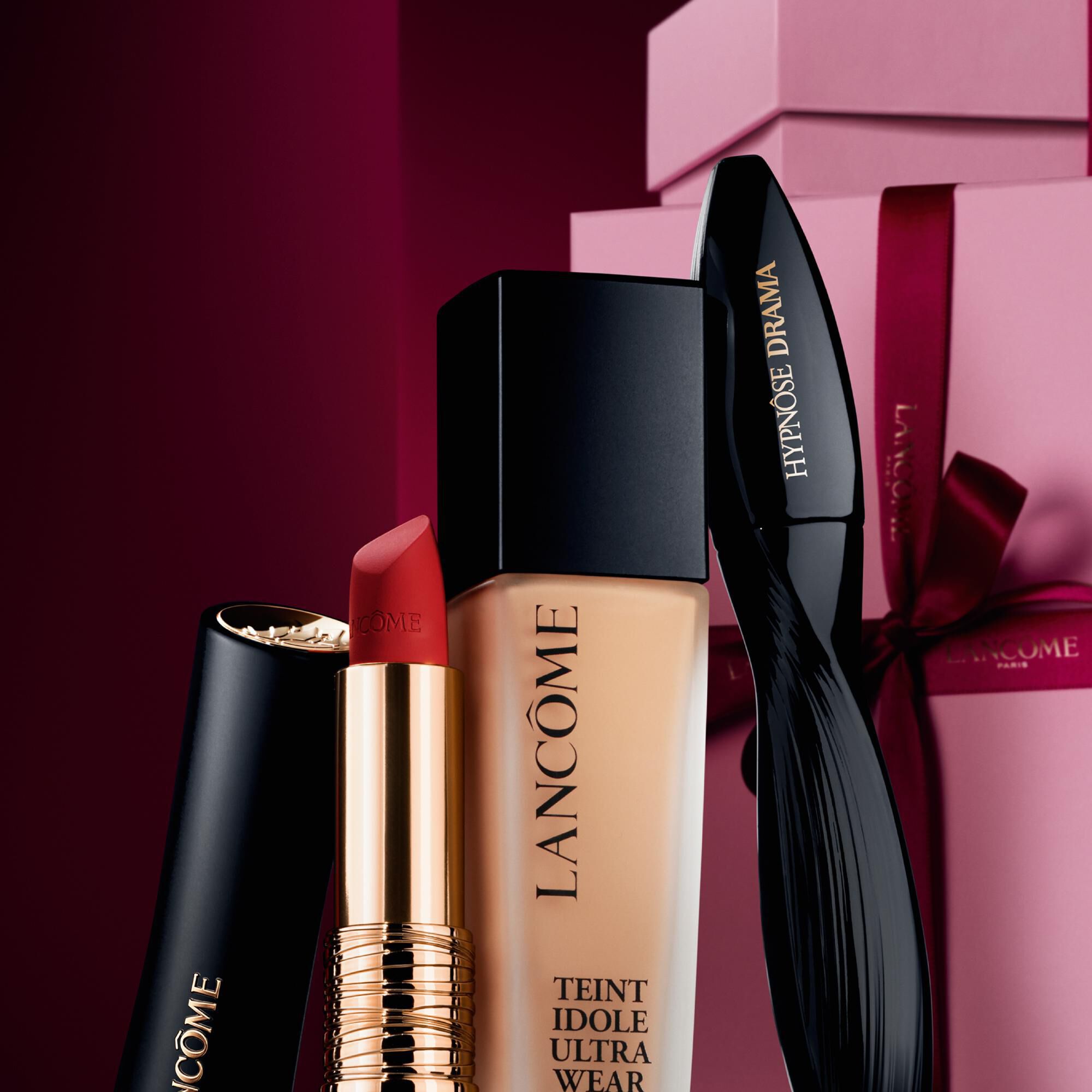 Image of Hypnose Drama, TIUW & L'Absolu Rouge standing in front of a pile of pink and dark red gift boxes, set against a dark red background. 