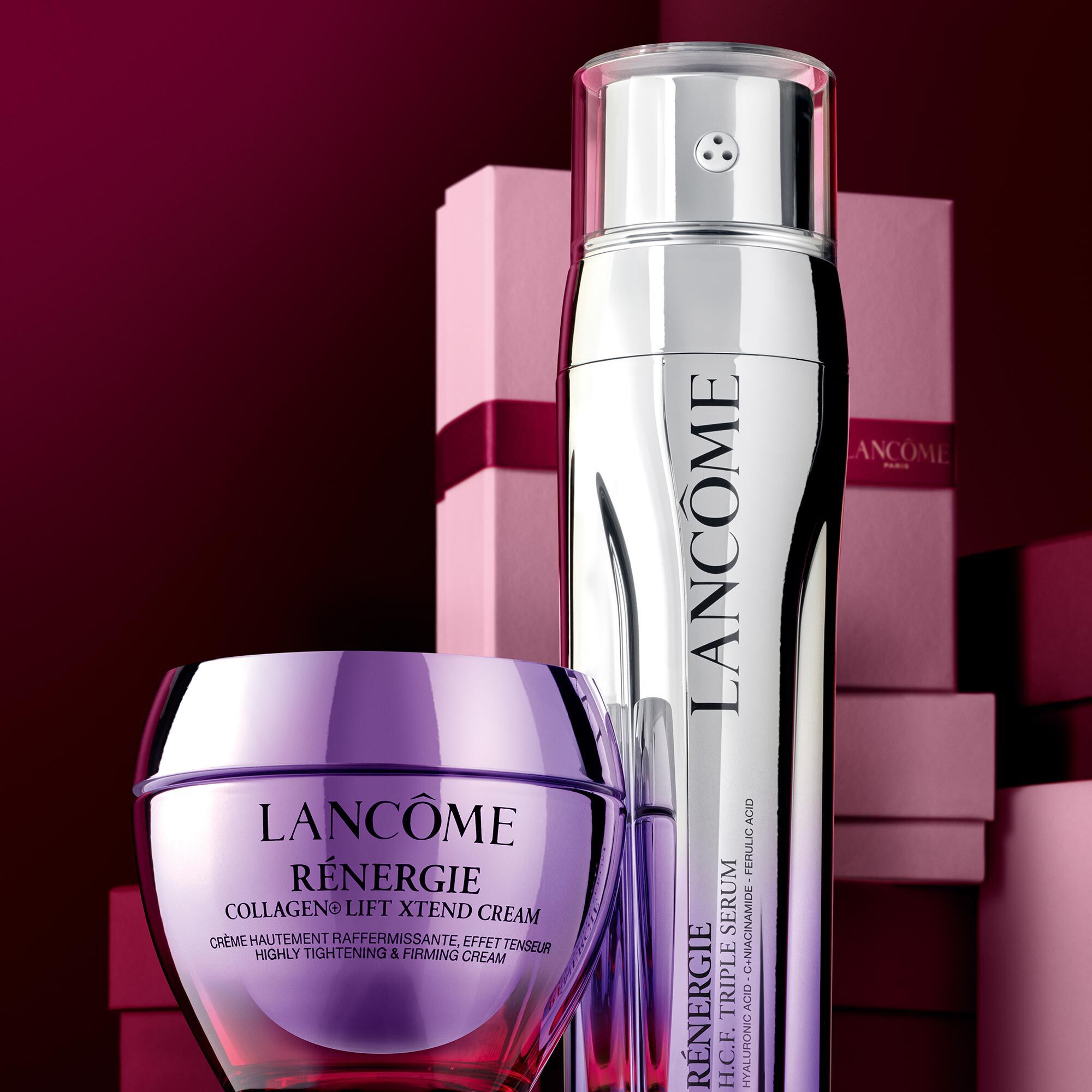 Image of Renergie Collagen Cream & Renergie Triple Serum standing in front of a pile of pink and dark red gift boxes, set against a dark red background.