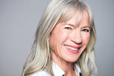 A smiling older woman with long, silver hair and a warm expression.
