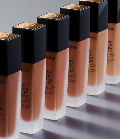 A row of foundation bottles arranged in a gradient, showcasing various skin tone shades against a sleek, neutral background.