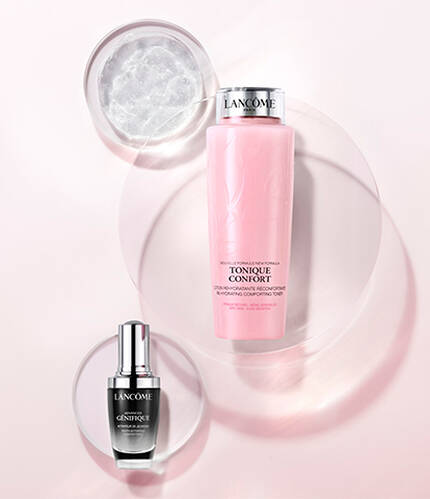 A minimalist display featuring two skincare products on a soft pink background: a black serum bottle and a pink lotion bottle, surrounded by circular, translucent shapes.