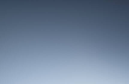 A close-up of Lancome makeup products, including a compact, foundation, and a concealer tube, set against a warm brown background.