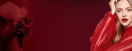 A woman in a dramatic red outfit poses next to a red product with roses, set against a dark red background. Her makeup features bold red lips, and she has long, flowing hair.