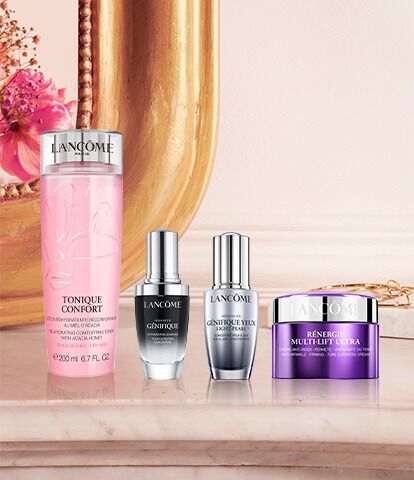 A elegant display of Lancome skincare products, including a pink toner and various serums and creams, arranged on a marble surface with ornate home decor in the background.