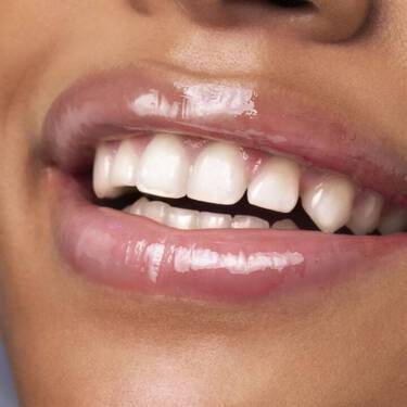 A close-up shot of a woman’s lips with Lancome’s Juicy Tubes Lipstick in Tickled Pink applied.