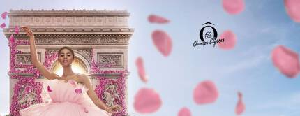 A dancer in a pink tulle dress poses gracefully in front of the Arc de Triomphe, surrounded by floating pink petals. A logo is featured on the right side.