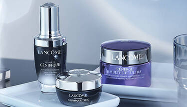 Three Lancome skincare products (Genifique serum, Genifique eye cream, and Renergie Multi-Lift Ultra) are displayed on a white tray.