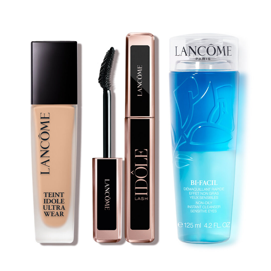 A collection of three Lancome beauty products: a foundation bottle labeled "Teint Idole Ultra Wear," a mascara tube labeled "Idole Lash," and a blue makeup remover labeled "Bi-Facil."