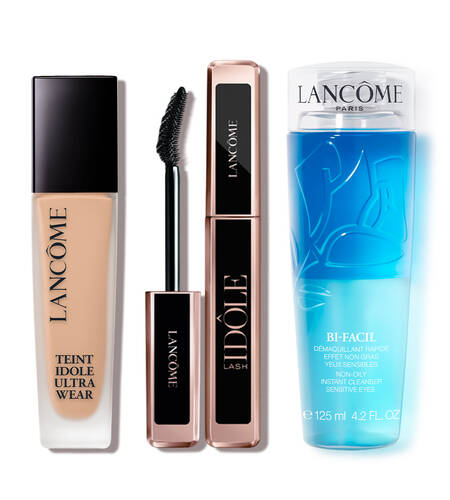 A collection of three Lancome beauty products: a foundation bottle labeled "Teint Idole Ultra Wear," a mascara tube labeled "Idole Lash," and a blue makeup remover labeled "Bi-Facil."