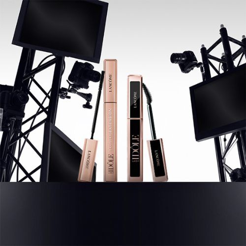 A sleek display featuring Lancome mascara products, surrounded by cameras and studio equipment, set against a gradient background.