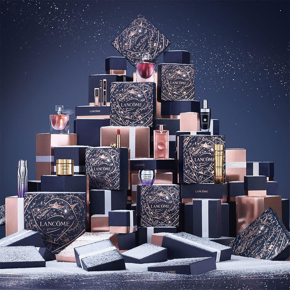 A decorative display of Lancome beauty products and gift boxes arranged stylishly against a dark, sparkly background.
