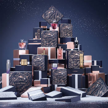 A decorative display of Lancome beauty products and gift boxes arranged stylishly against a dark, sparkly background.