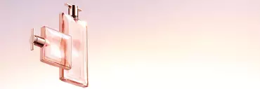 Two elegant perfume bottles in soft pink hues, set against a gradient background that transitions from light pink to a soft peach.