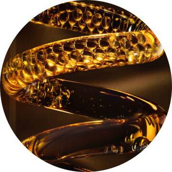 Close-up of twisting amber glass, showcasing intricate patterns and bubbles reflecting light.