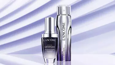 Two Lancome serums, Advanced Genifique and Renergie H.C.F. Triple Serum, are showcased against a light purple background with diagonal shadow stripes.