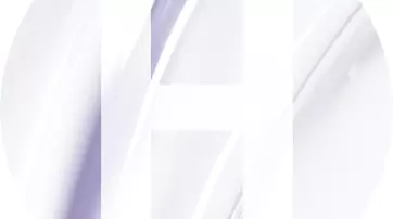 A circular design featuring a large, white letter "H" overlaid on a soft, abstract background of pale colors and smooth curves.
