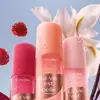 Three spray bottles of Lancome "La vie est belle" Hair & Body Mist in different shades of pink and orange, set against a background of raspberries and a white flower.