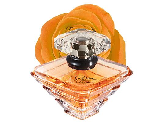 A bottle of Lancôme Trésor perfume, featuring an elegant design, with a soft orange rose in the background.